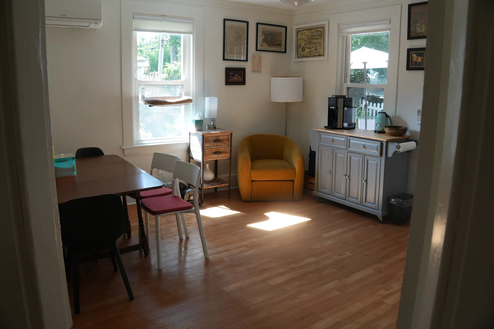 A tidy, sunlit dining room with a cleared table and polished wood floor