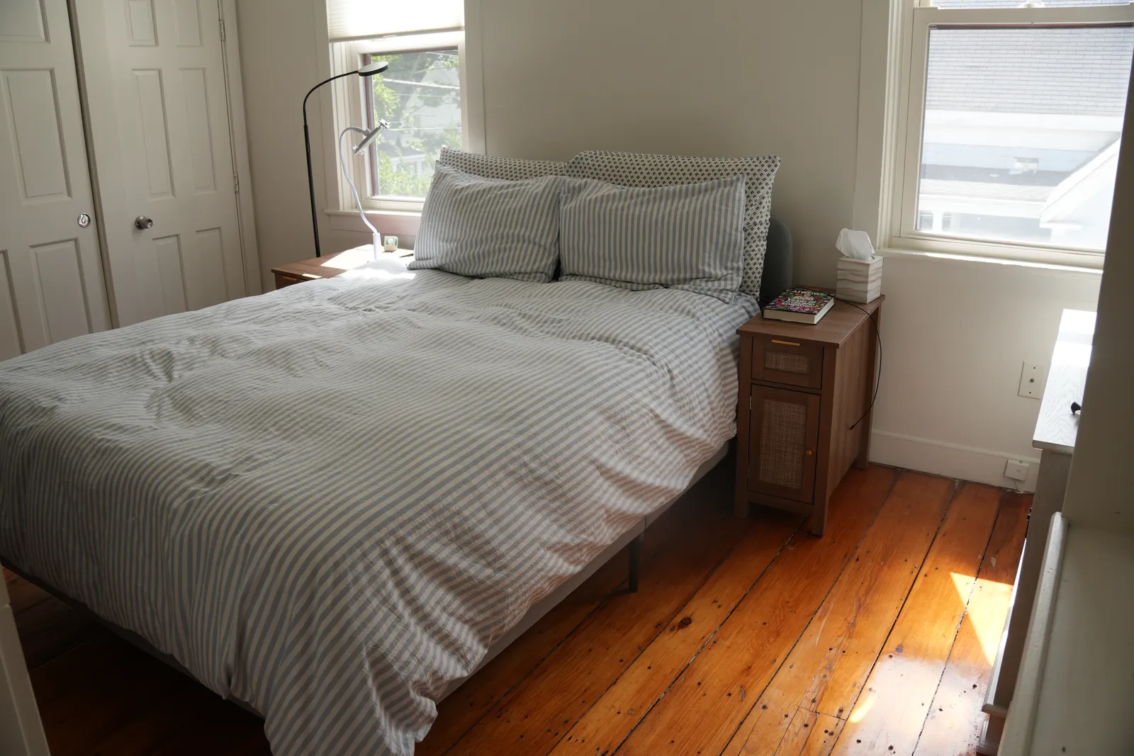A freshly made bed with crisp striped linen in a bright bedroom